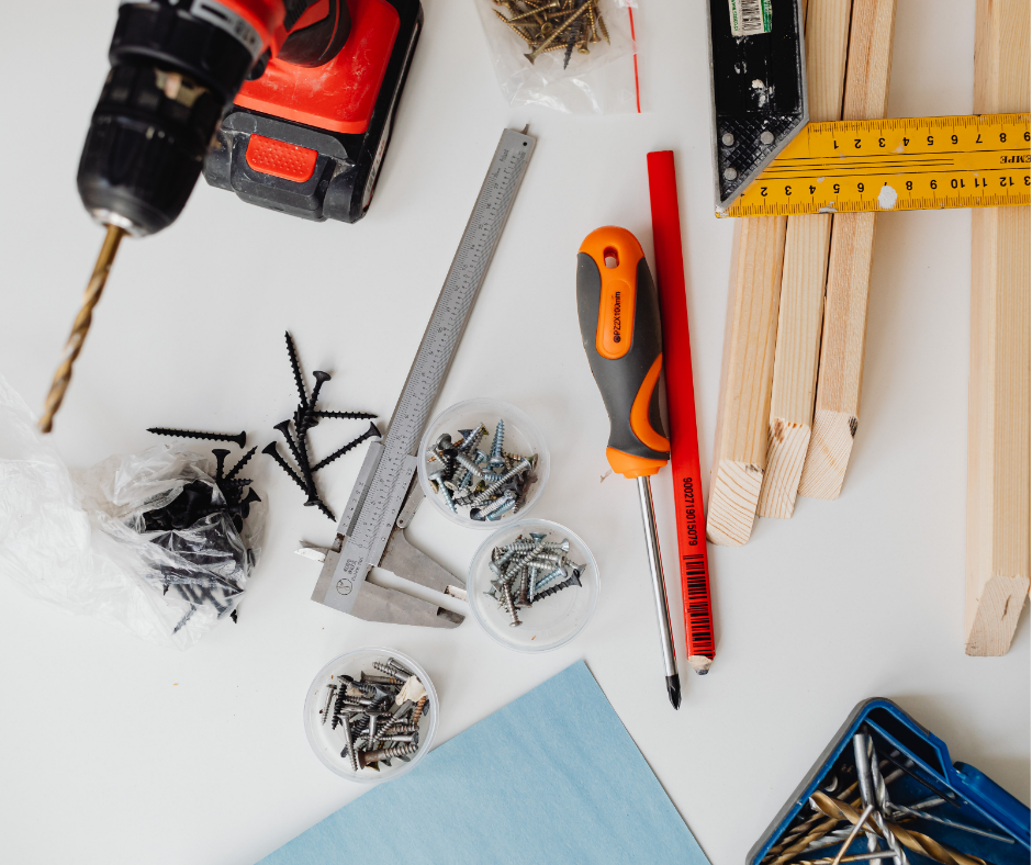 Dụng cụ thi công gồm máy khoan, vít và thước đo trên bàn.