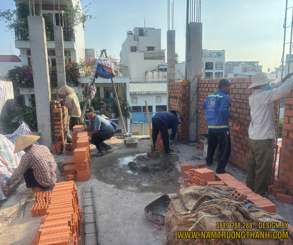 Đội thợ xây tường gạch đỏ phần thô trên lầu nhà phố.