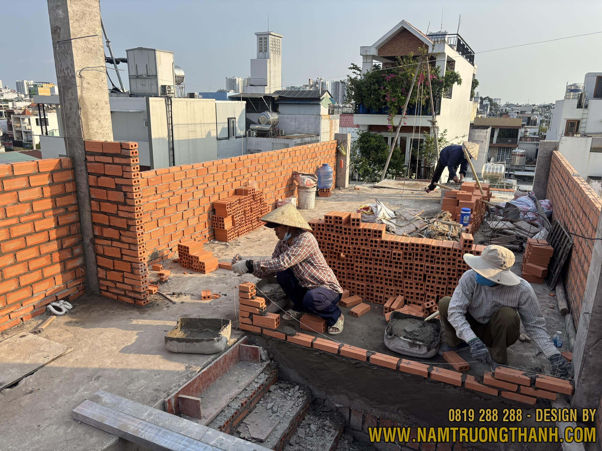 Thợ nề đang xây tường gạch ống trên sàn sân thượng nhà phố.